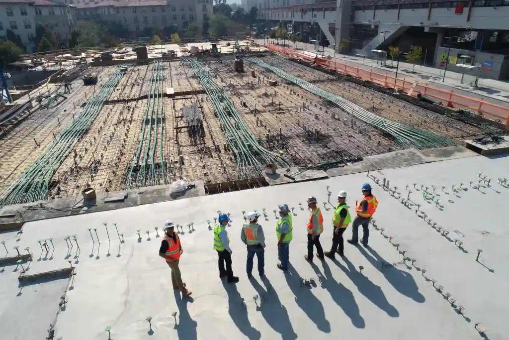 Equipe de engenheiros e especialistas em construção analisando o andamento de uma obra civil em um canteiro de obras urbano, destacando a importância de entrevistas com especialistas na construção civil.