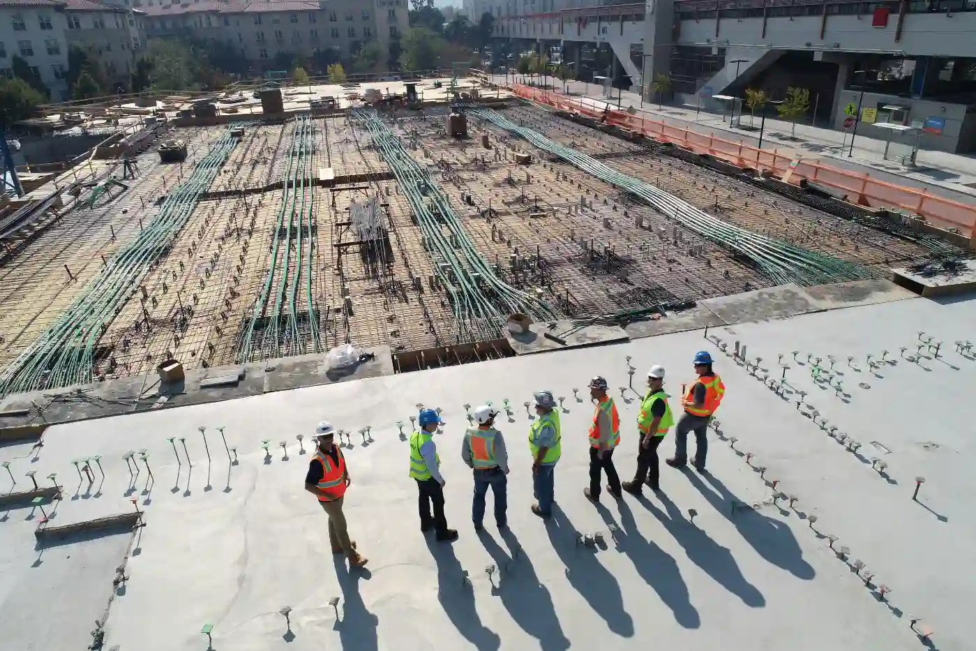 Equipe de engenheiros e especialistas em construção analisando o andamento de uma obra civil em um canteiro de obras urbano, destacando a importância de entrevistas com especialistas na construção civil.
