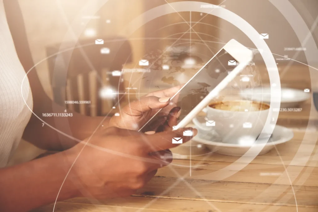 Mãos usando um tablet com overlay de ícones de e-mail e dados digitais, simbolizando o futuro do empreendedorismo digital, automação e comunicação online.