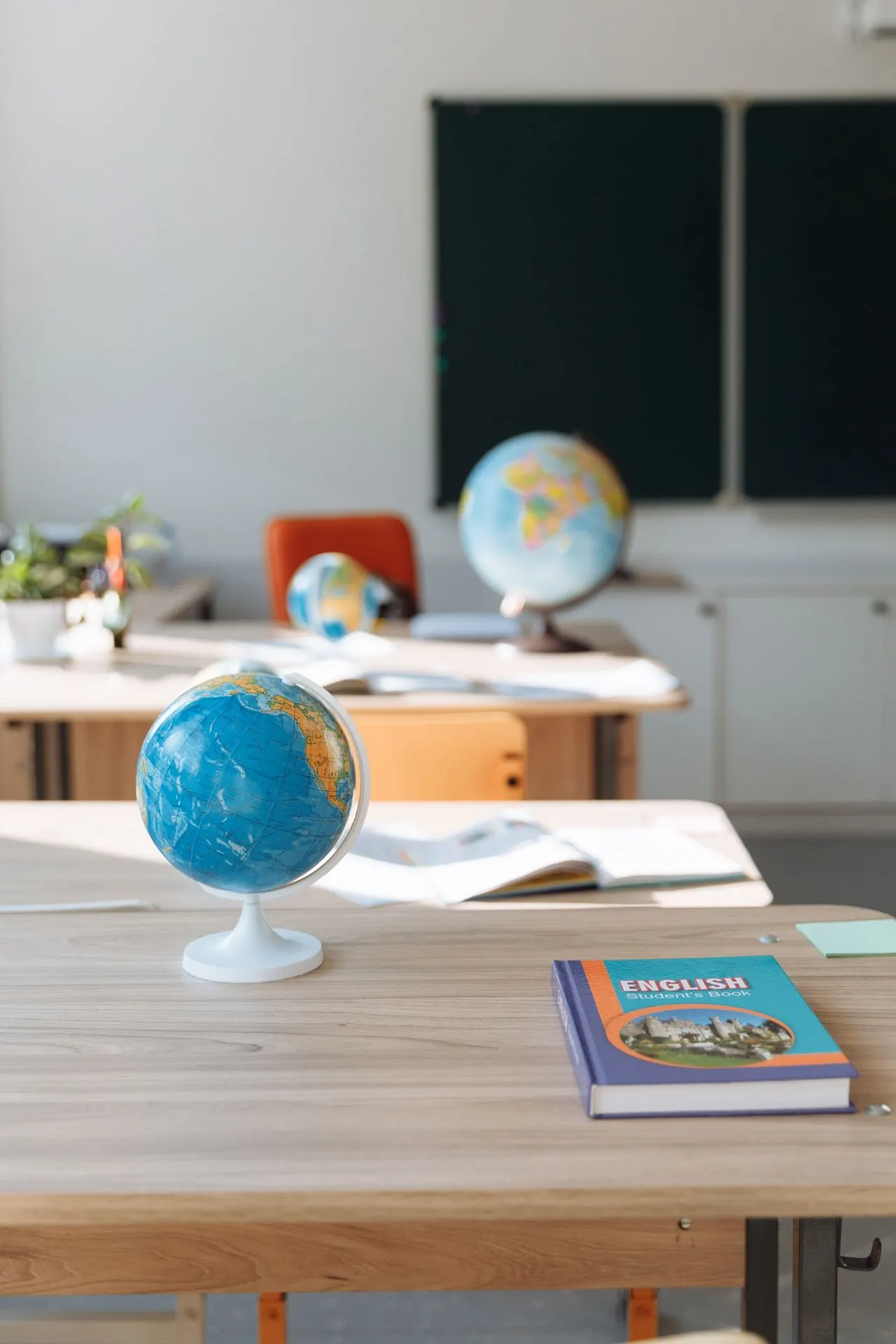 Sala de aula com globo terrestre e livro de inglês sobre a mesa, com ambiente educativo e lousa ao fundo; ideal para Escola de Inglês do Brasil: Guia Completo.